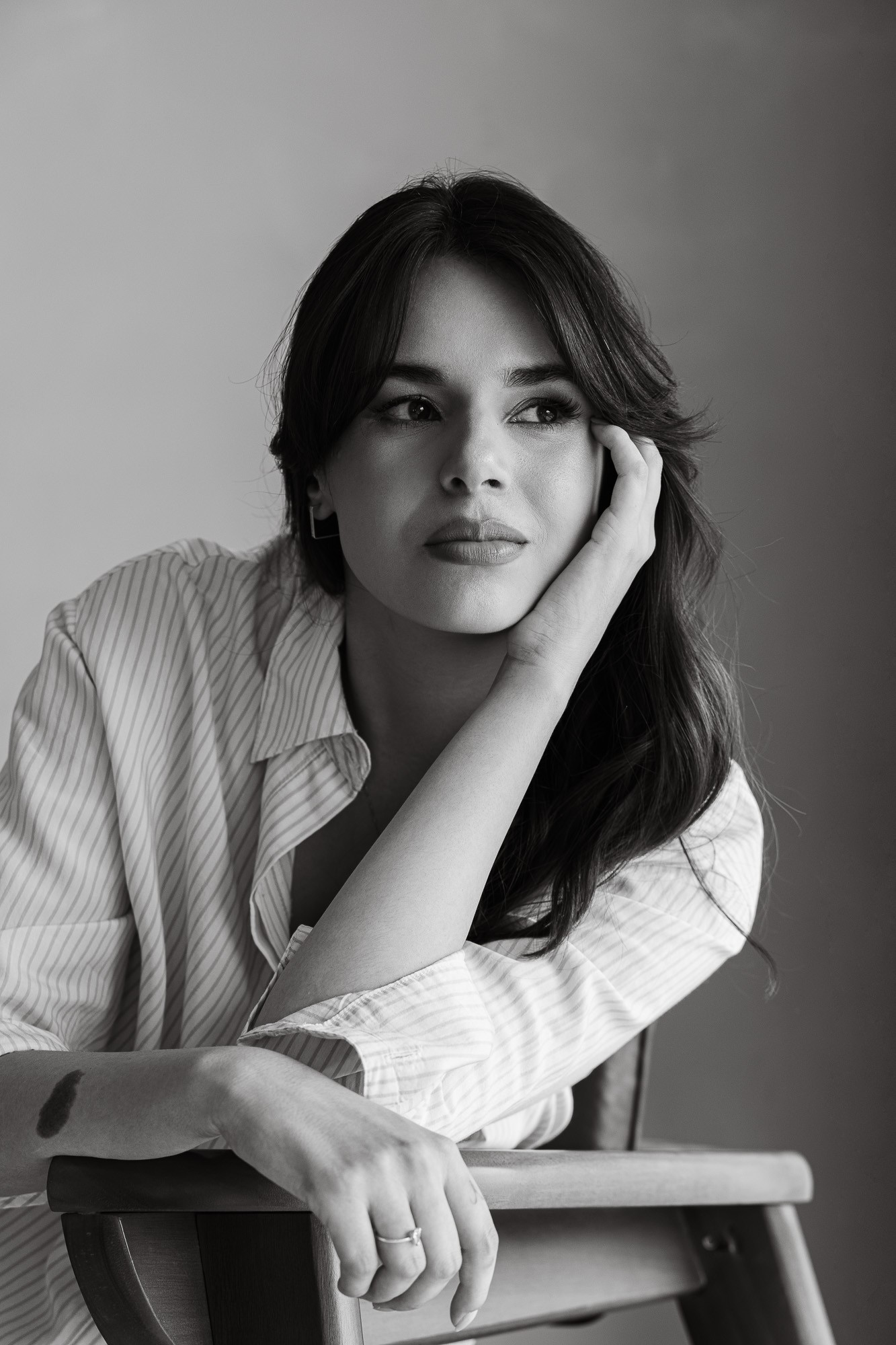 Portrait of a man with brown hair and glasses on a flat gray background.